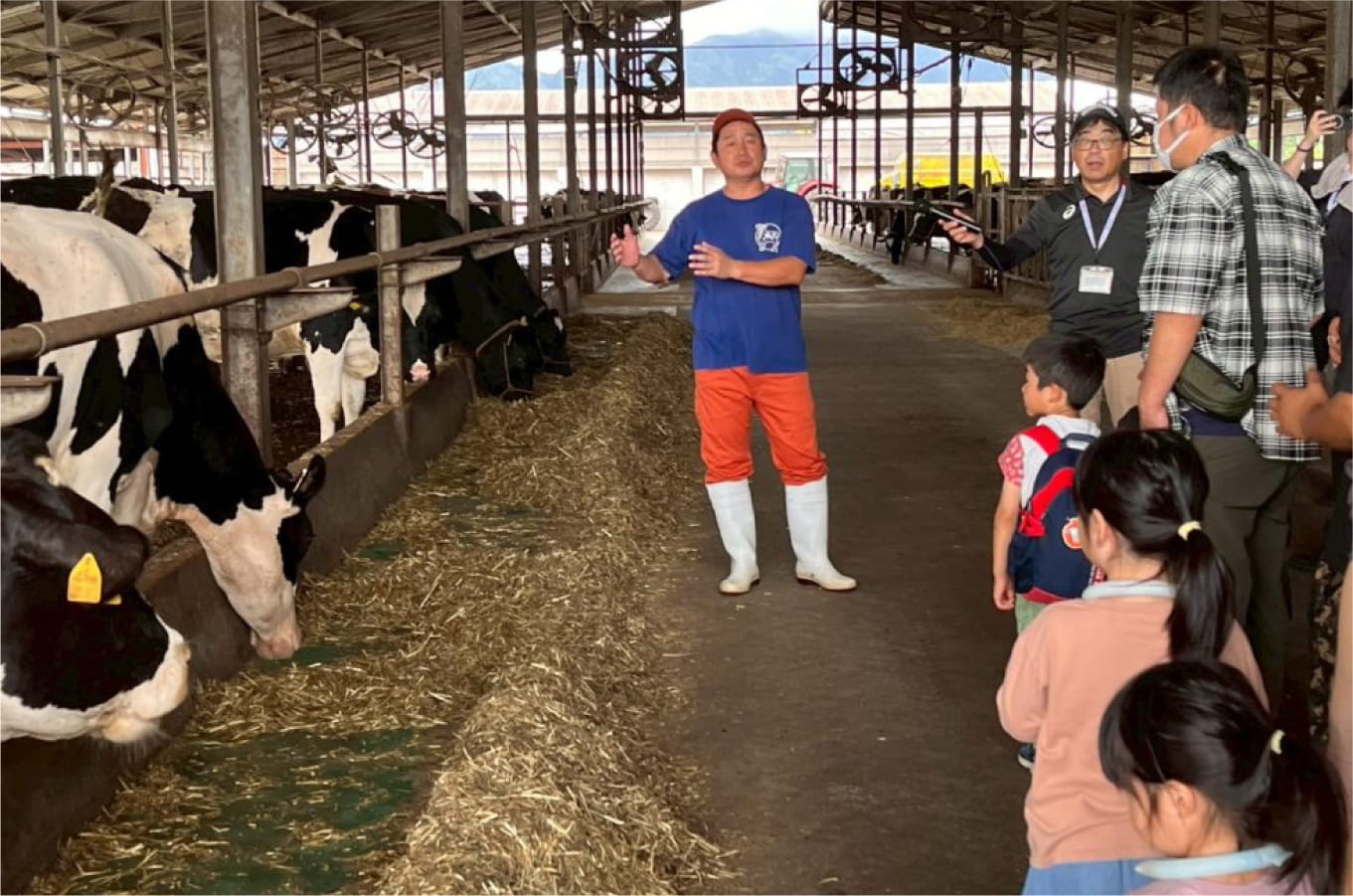 産地見学の様子（牧場で生産者の説明を聞く参加者）